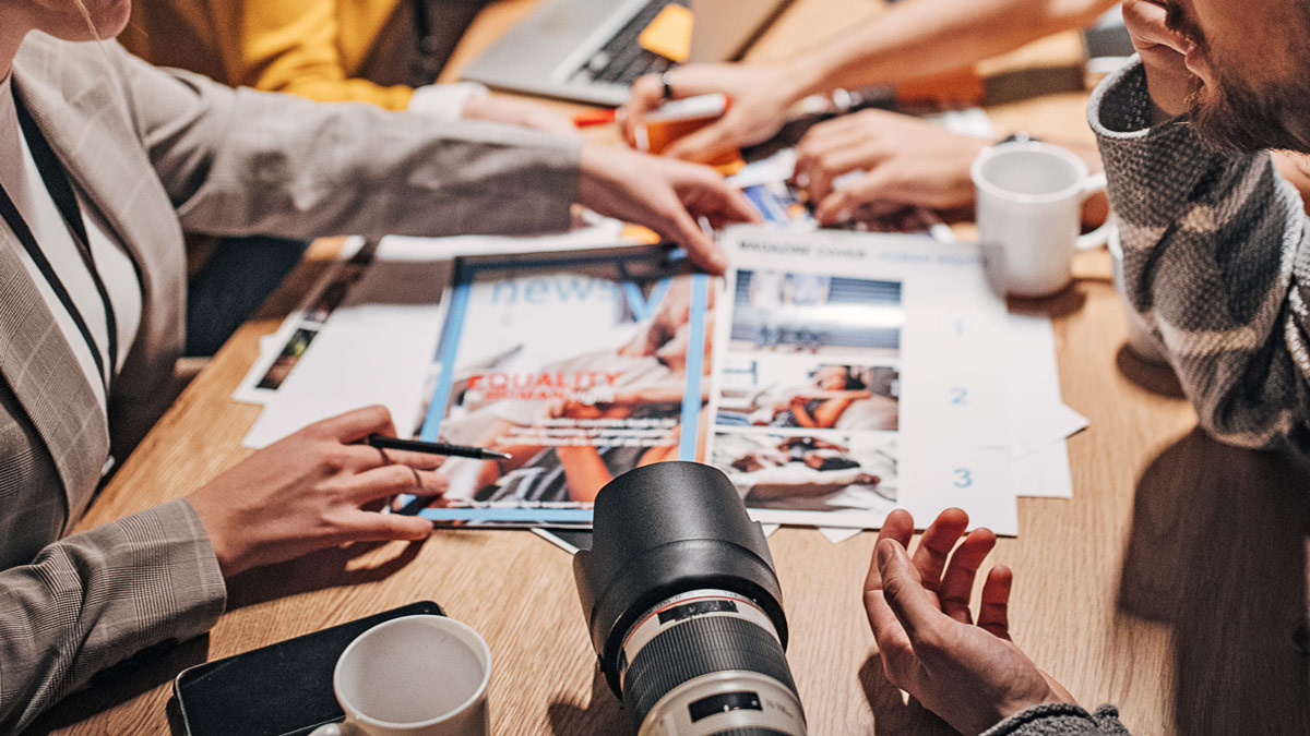 A group of people at a table looking at marketing materials.