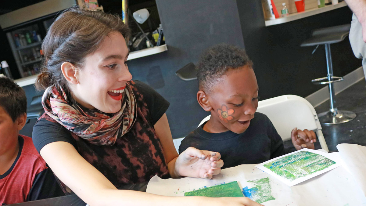 An RIT student and middle-schooler work on an art project.