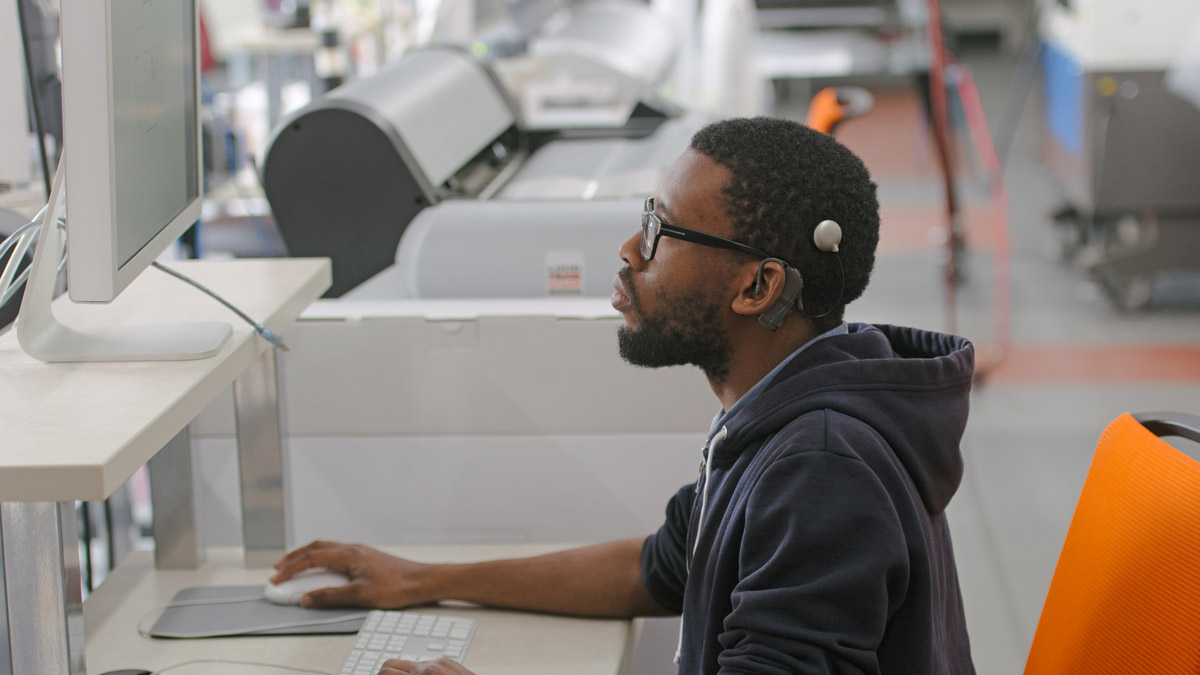 Student in lab looks up at computer monitor.