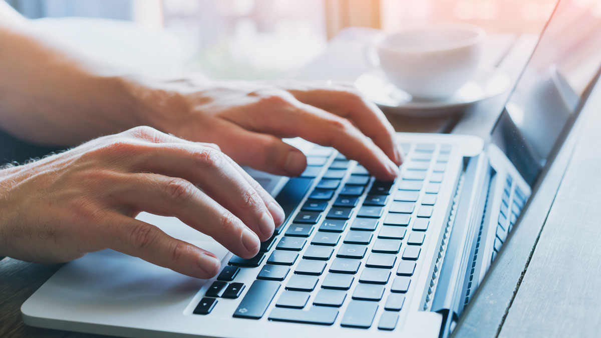 Close up of hands typing on a laptop.