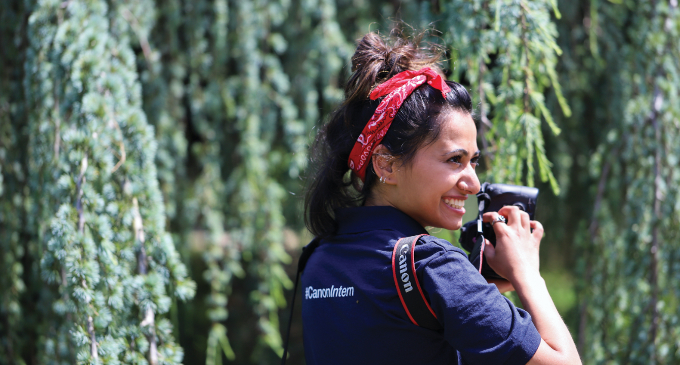 Student with a camera wears a shirt labeled Canon Intern.