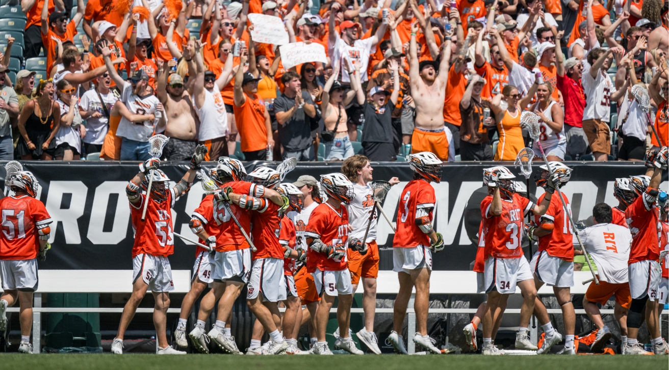 Lacrosse team celebrating in front of fans