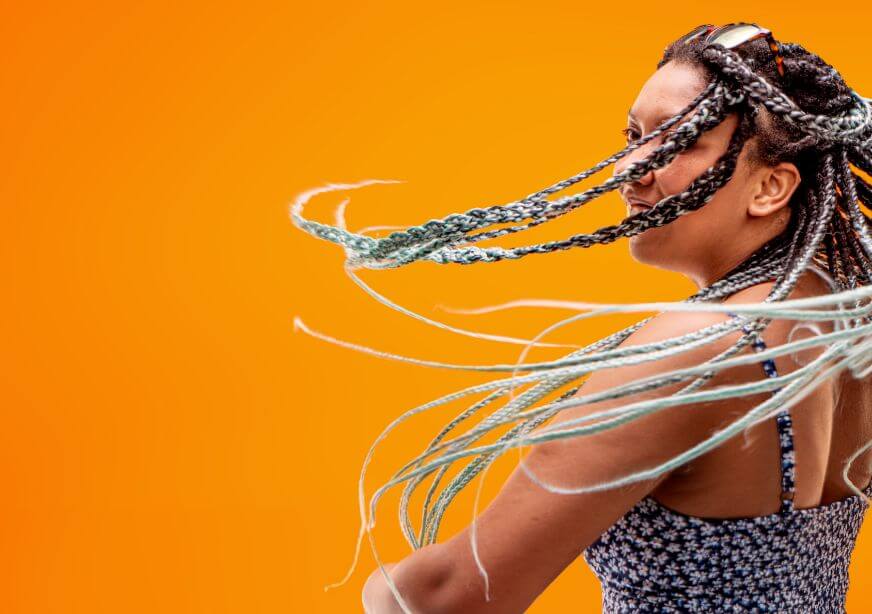 A woman with long braided hair smiling and spinning.