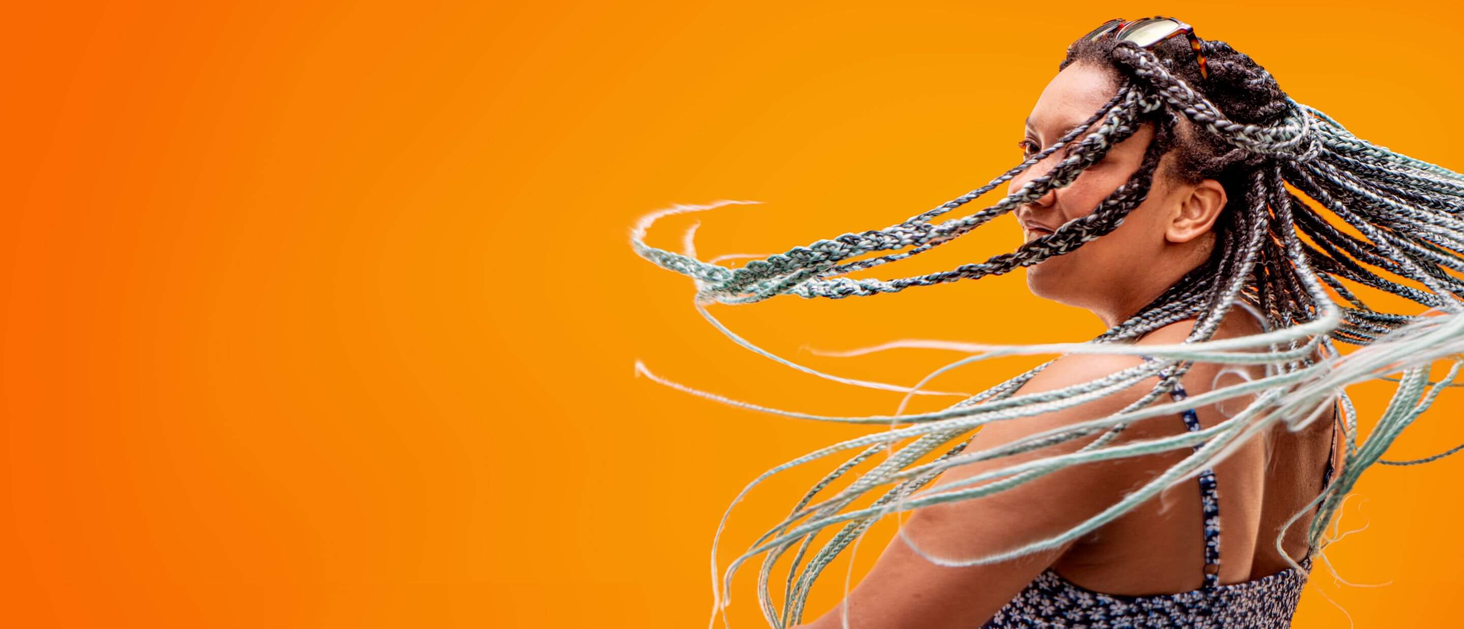 A woman with long braided hair smiling and spinning.