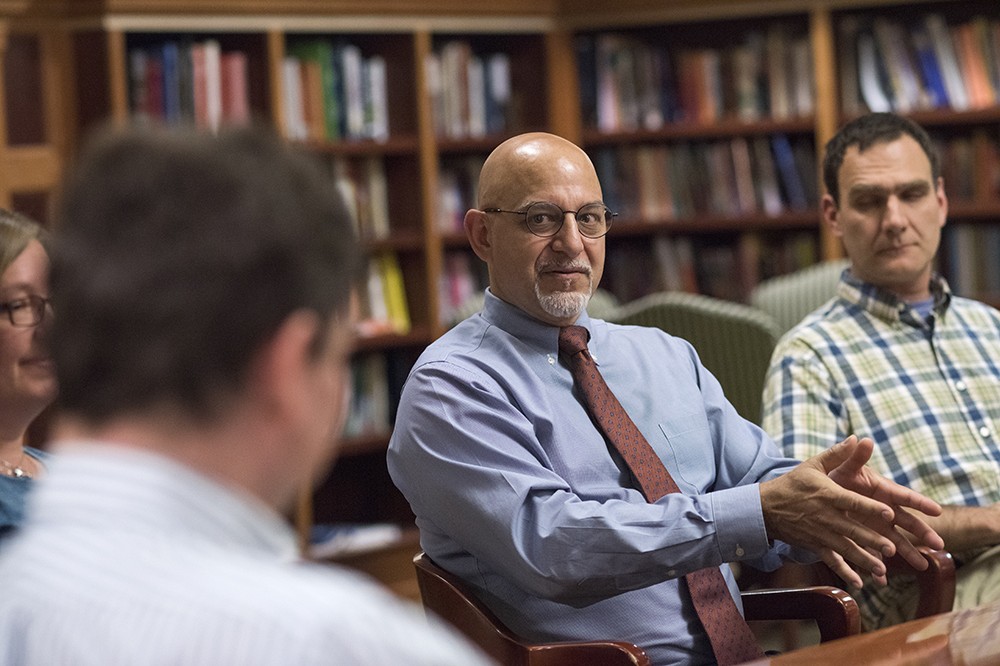 Man speaking with faculty around a table