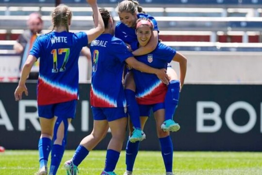 four female soccer players celebrate a goal