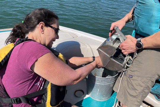 'A woman samples sediment in Lake Ontario as part of her extensive research in marine debris. '