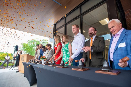 Dean Jacqueline Mozrall, along with other RIT and community leaders ring the opening bell, awash with biodegradable confetti, to signify the official opening of the college’s expansion. 