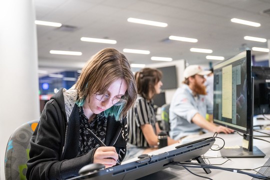 a student draws on a pad connected to a computer.