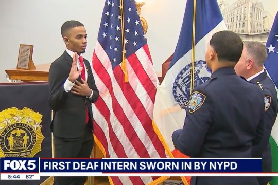 'Heriberto Almone appears on the left getting sworn in by offers standing on the right with an american flag in the background.'