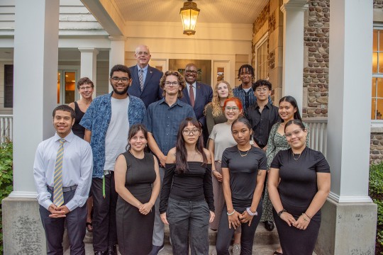 'a group of students stand with Dave and Nancy Munson at the entrance to Liberty Hill, the Munsons residence.'