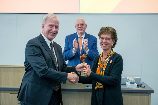 'a man and woman shake hands in front of R I T President David Munson.'