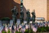 Four female members of the armed forces appear in salute position in front of a display of american flags.