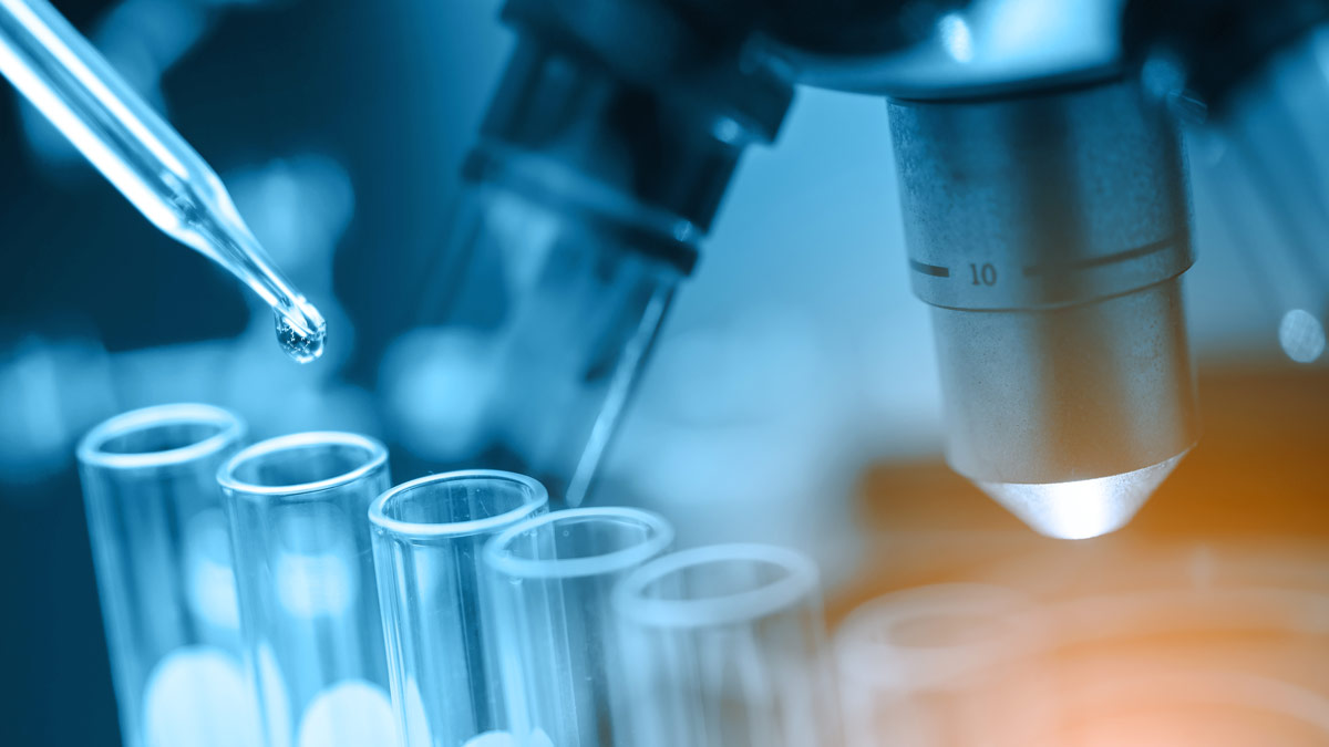 Extreme close up of test tubes with a pipette placing a drop into one of them.