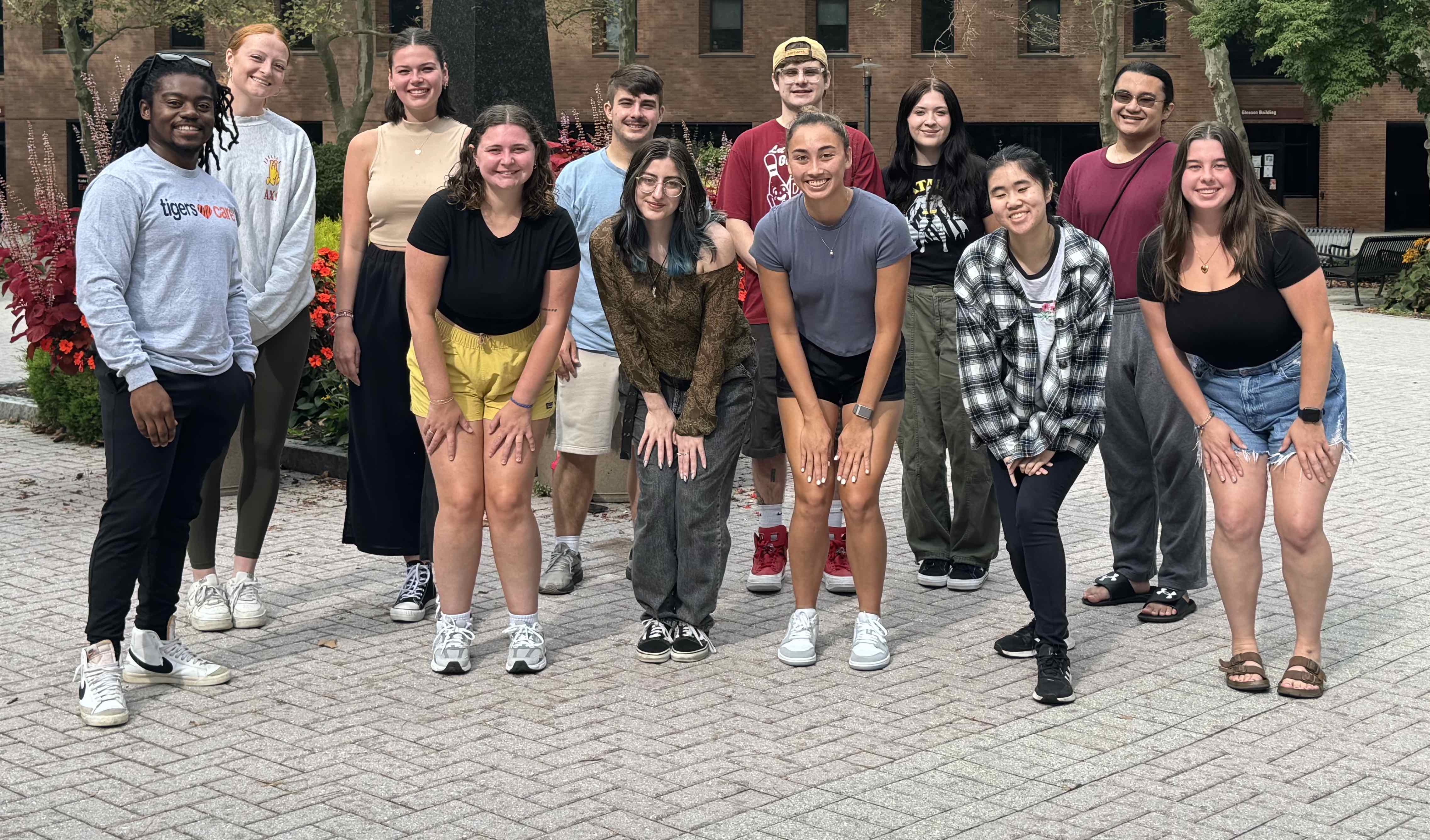 12 people posing for a photo by the sentinel, at RIT.