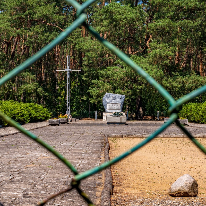 a color photograph with a view through a chain link fence to a memorial stone.