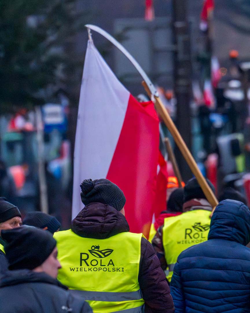 a color photograph of the back of a protestor holding a large red and white flag.