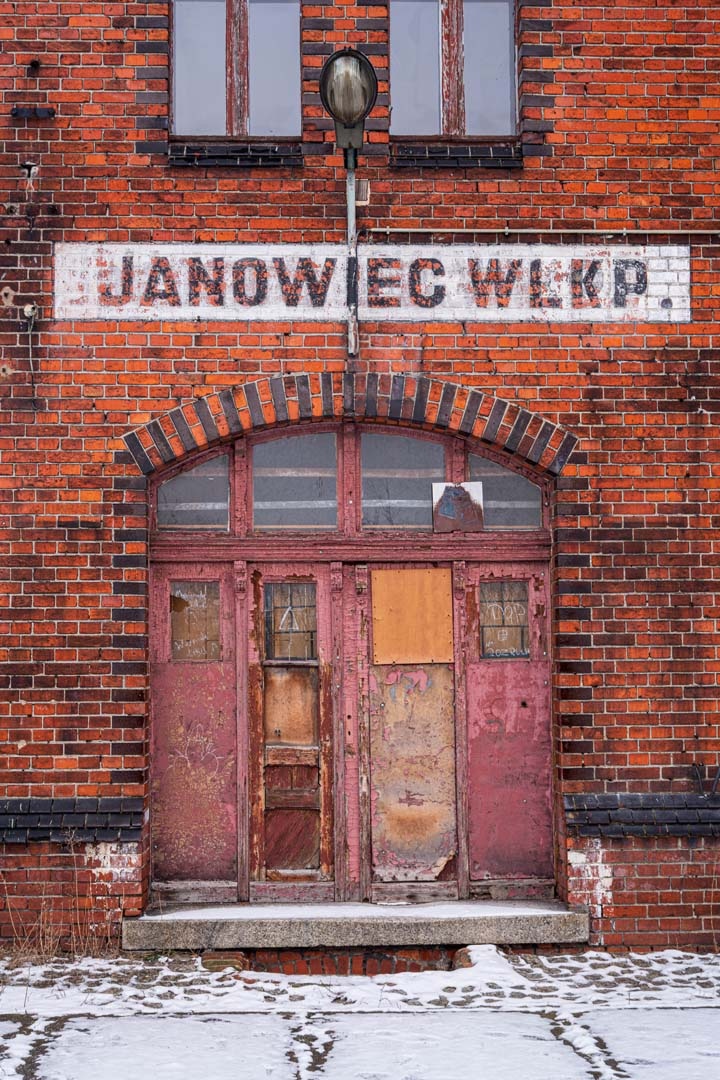 a color photograph of a boarded up double door entry to a brick building.