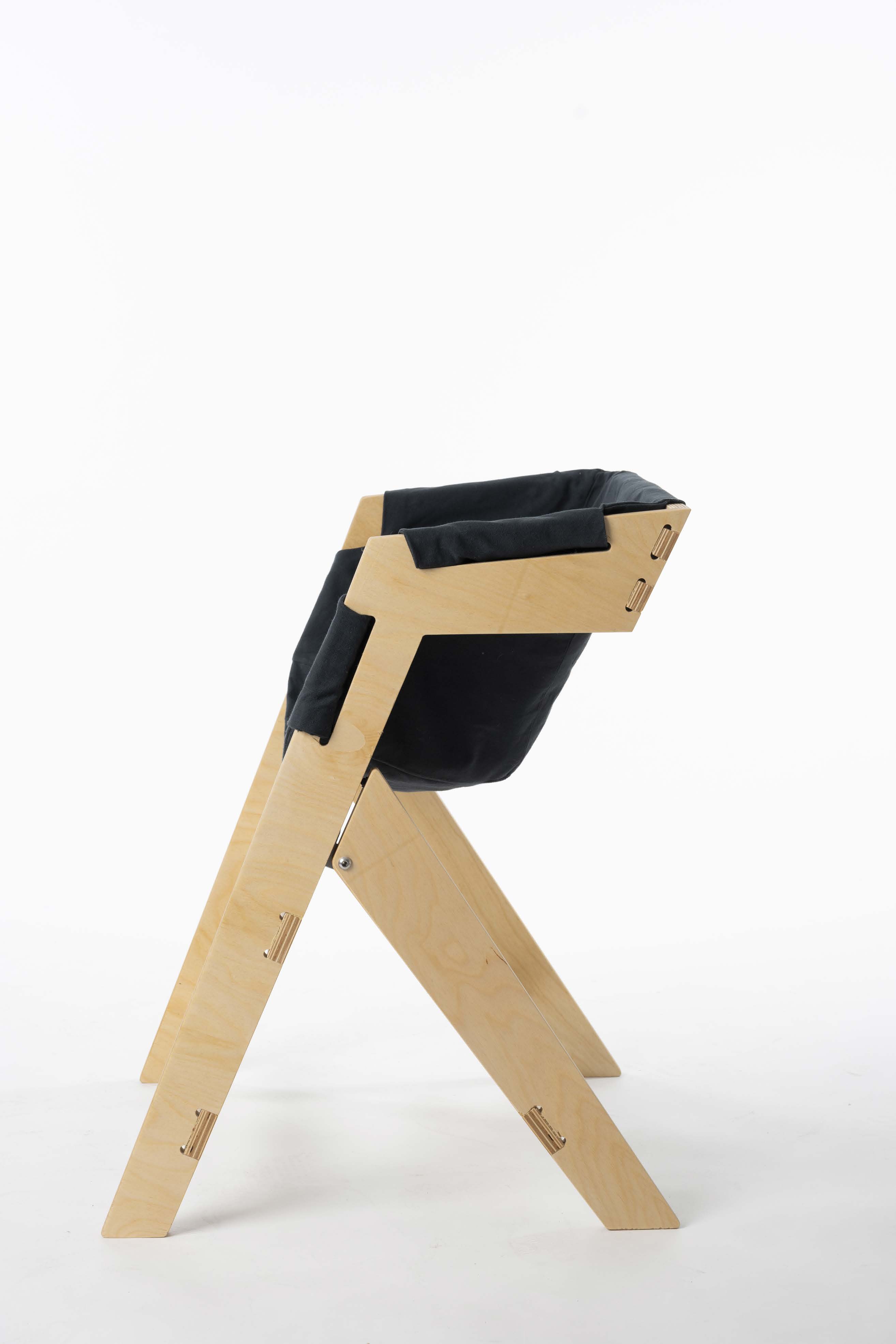 a view of a folding chair design with natural wood arms and legs and a black fabric seat and back.