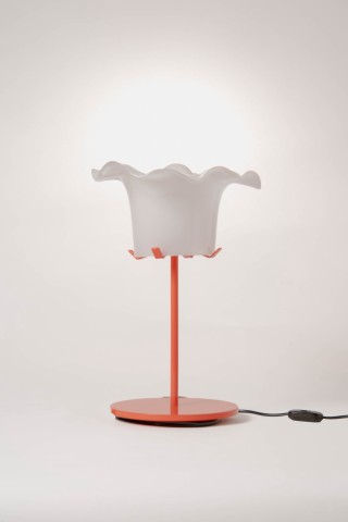a lamp with a red metal base and glass shade against a grey background.