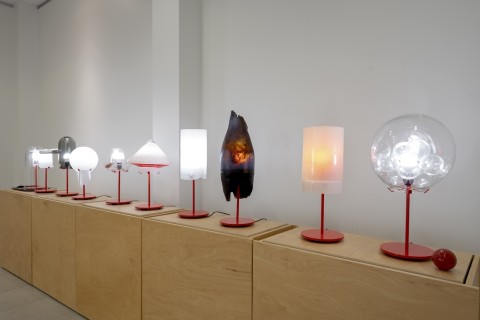 a view into the Grid Space gallery with a view of the display of lamps on wood stands. 