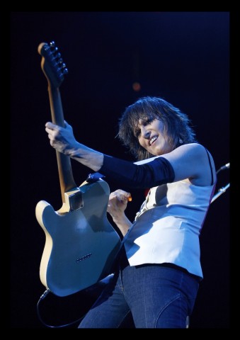 Color photograph of musician Chris Hynde playing a guitar on stage.