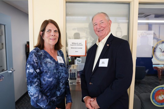 a man and a woman stand in front of the newly dedicated lounge.